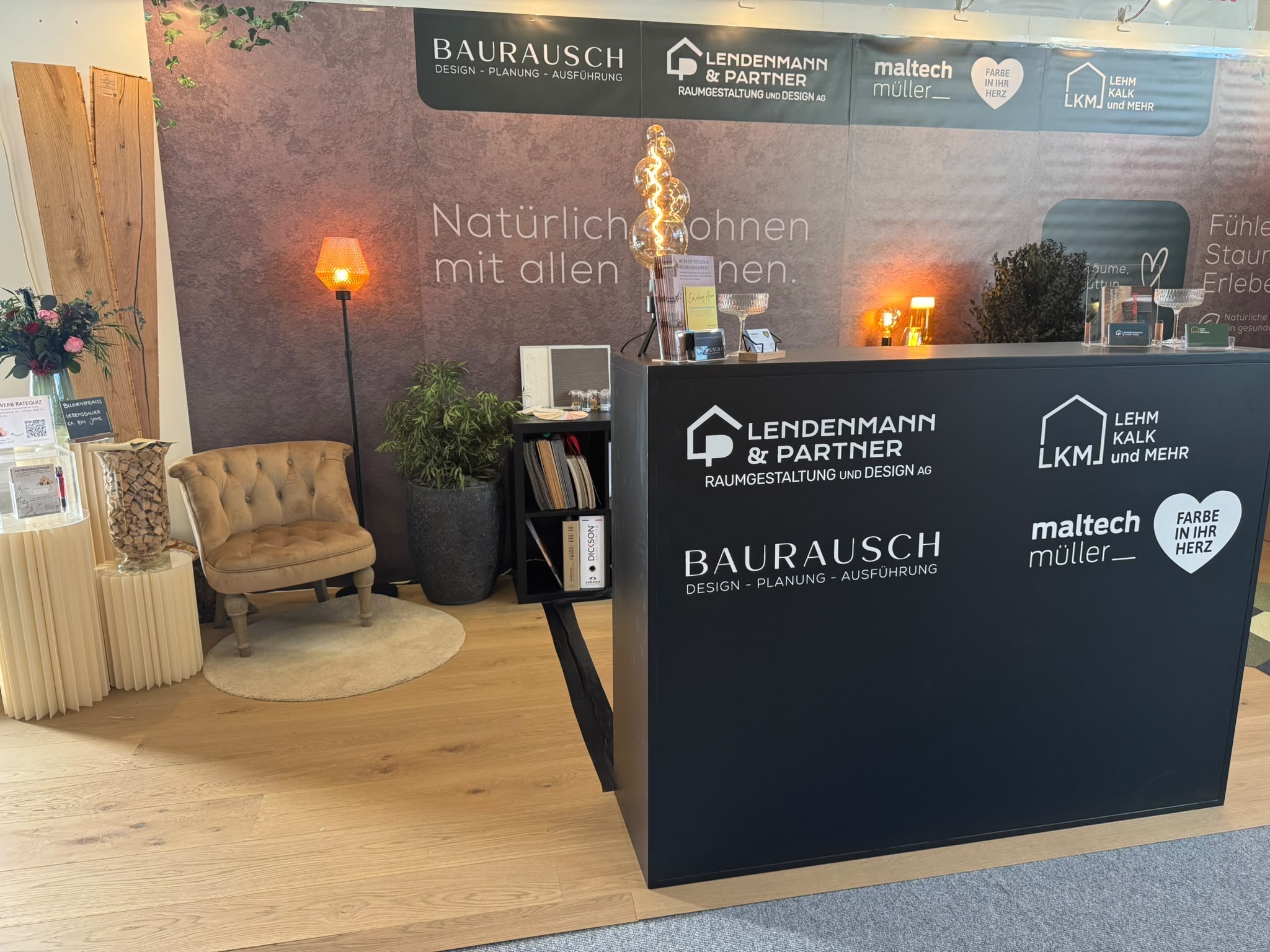 Gemeinsamer WEGA-Stand 2026 von Maltech Müller, BAURAUSCH, Lendenmann & Partner und LKM mit Materialmustern und warmem Licht